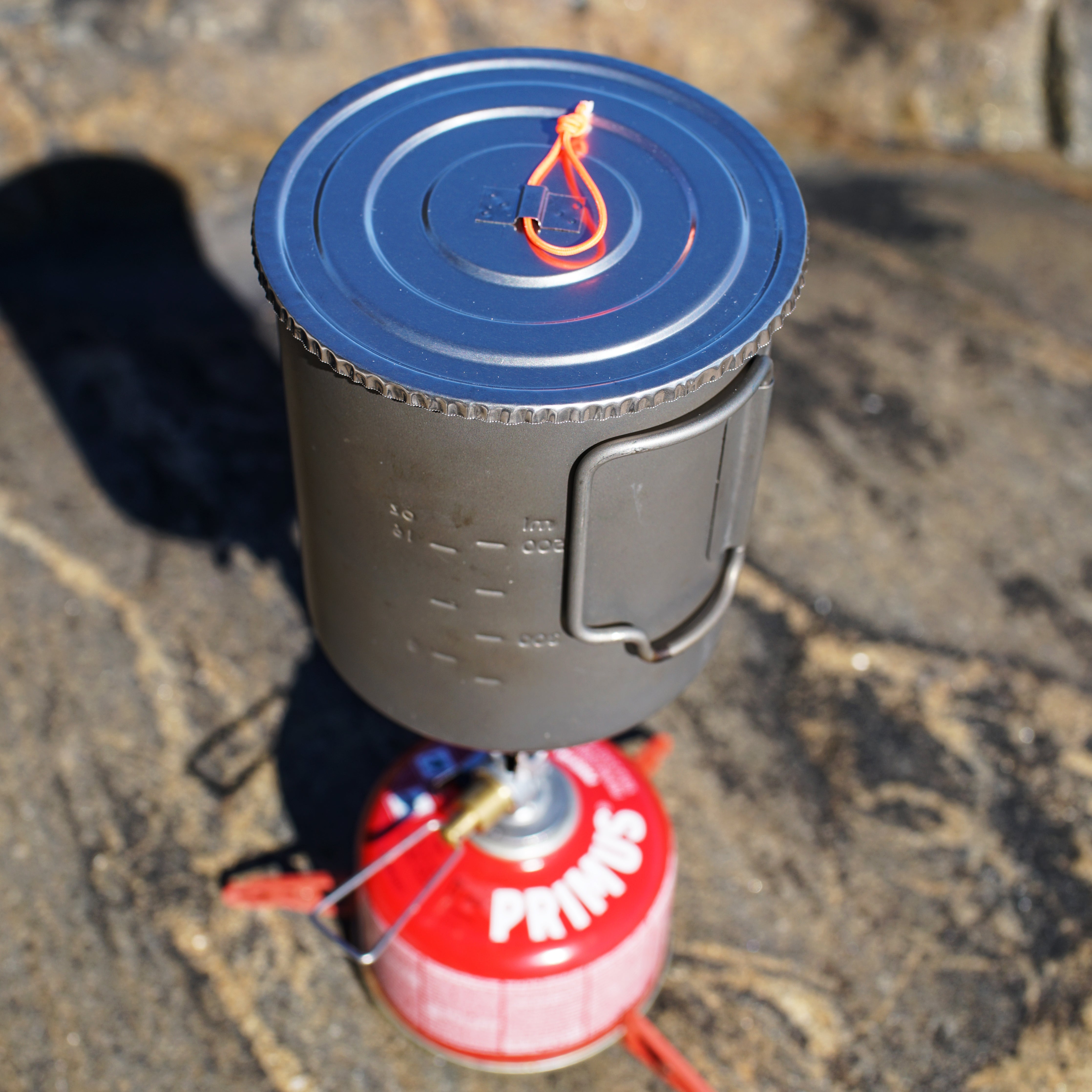 FeatherLid titanium lid fitted to a backpacking pot on a gas stove